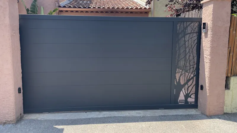 Portail coulissant en aluminium gris anthracite à lames horizontales et panneau perforé, entre deux piliers enduits