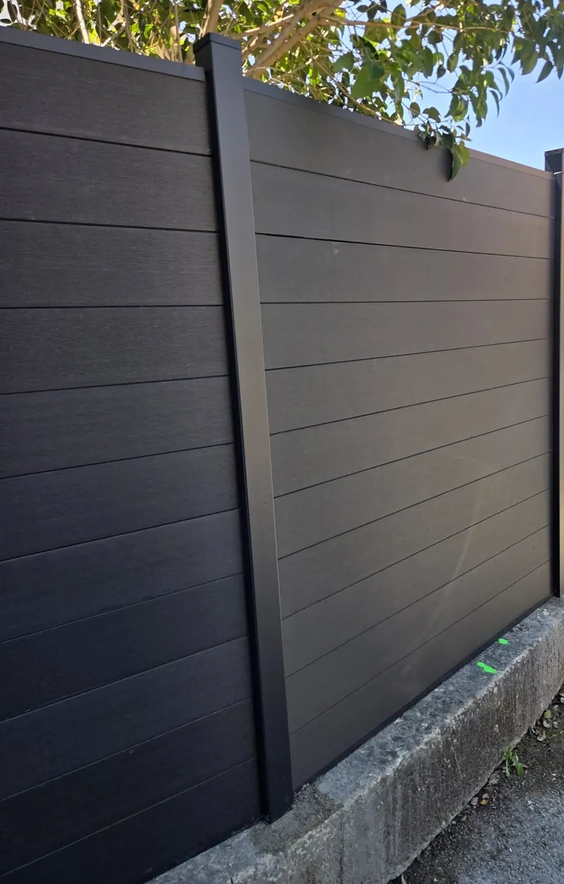 Détail d'un poteau aluminium et des lames composite anthracite fixés sur un muret béton existant