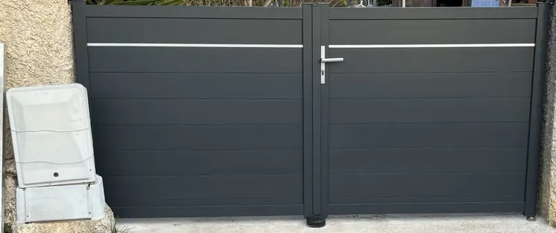 Portail battant deux vantaux en aluminium gris anthracite à lames horizontales, posé entre des piliers existants